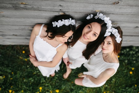 three beautiful girls on the background of a wooden houseの写真素材