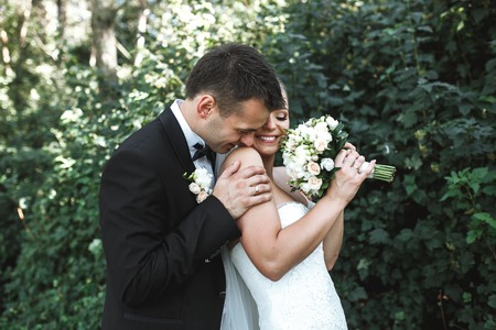 Beautiful wedding couple posing in the park on the background of foliageの写真素材