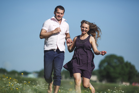 beautiful couple runs across the field and funの写真素材