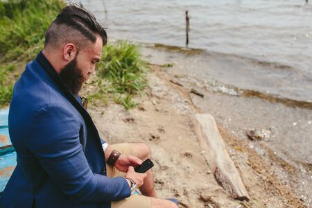American Bearded Man looks on the river bank in a blue jacketの写真素材