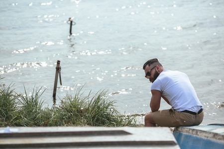 American Bearded Man looks on the river bank in a blue jacketの写真素材
