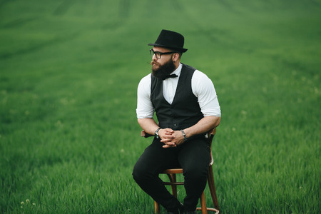 a man with a beard sitting on a chair on the fieldの写真素材