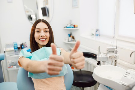 young girl sitting on a chair at the dentistの写真素材