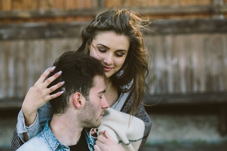 guy sitting on a chair and standing next to his girl wrapped in a plaidの写真素材