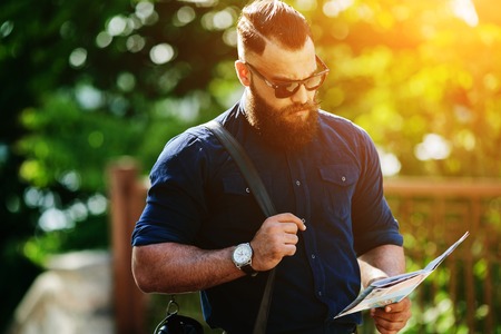 bearded man sitting and looking at a mapの写真素材