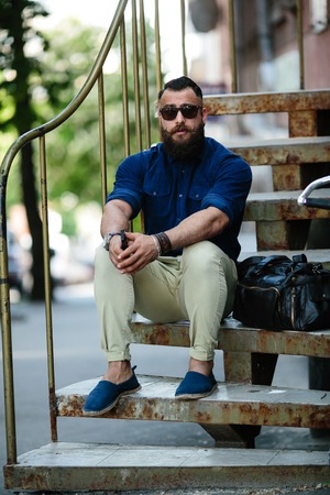 bearded man sitting on the stairs on the streetの写真素材
