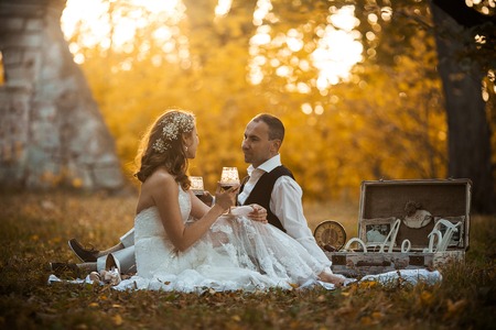 Beautiful wedding couple at a picnic under a tree drinking champagneの写真素材