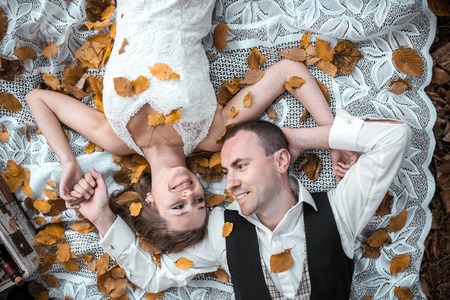 Beautiful wedding couple lying under a treeの写真素材