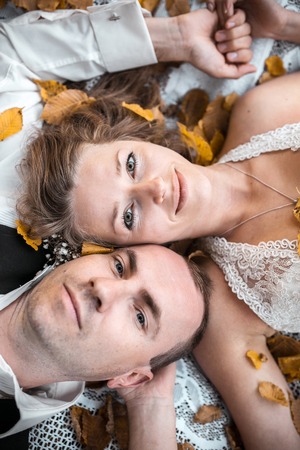 Beautiful wedding couple lying under a treeの写真素材