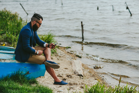 American Bearded Man looks on the river bank in a blue jacketの写真素材