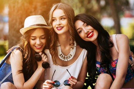 Three beautiful young girls posing against the backdrop of the park