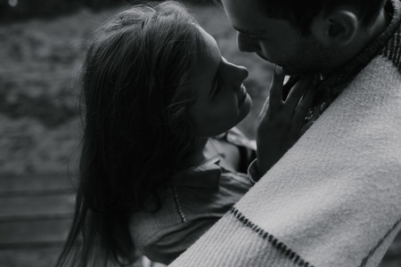 Young couple in love wrapped in plaid standing and looking at each otherの写真素材