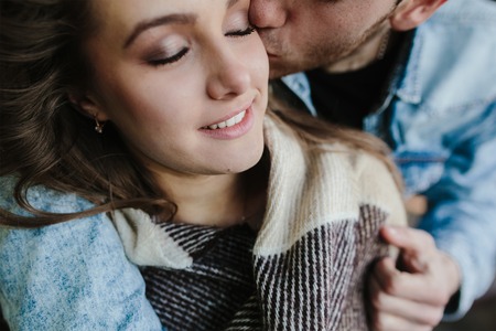 Young couple in love wrapped in plaid standing and embraceの写真素材