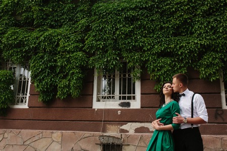 man and woman embrace on a background of building all covered with vinesの写真素材