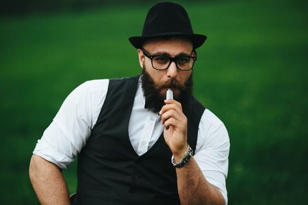 well dressed man with a beard smoking electronic cigaretteの写真素材