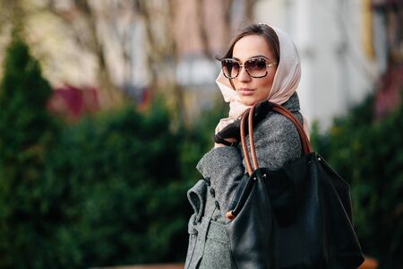 young beautiful happy girl in a coat posing at the parkの写真素材