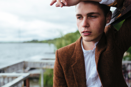 the young man posing on a pier on the background of waterの写真素材