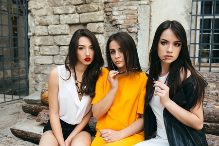 Three young beautiful girls posing against the backdrop of an abandoned buildingの写真素材