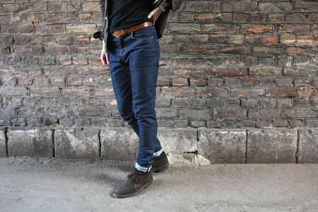Male model in jeans on the background of a brick wallの写真素材