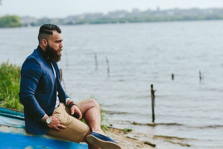 American Bearded Man looks on the river bank in a blue jacketの写真素材