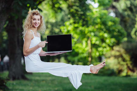 beautiful girl levitates in nature with laptopの写真素材