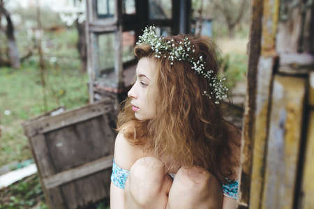 beautiful girl walks in the lush garden dressed in a wreathの写真素材