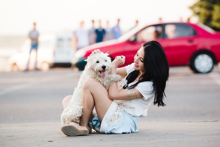 beautiful girl sitting on the street and playing with her dogの写真素材