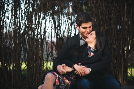 beautiful girl and her boyfriend resting together on a bench in the park