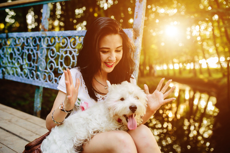 girl playing with a dog on the bank of the river near the bridgeの写真素材
