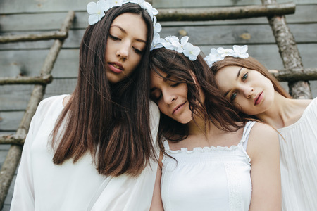 three beautiful girls on the background of a wooden houseの写真素材