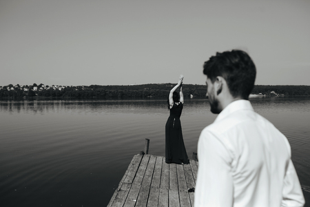beautiful young couple spends time on the wooden pier on the lakeの写真素材