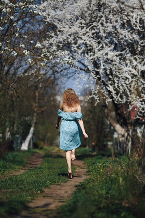 beautiful girl walks in the lush garden dressed in a wreathの写真素材