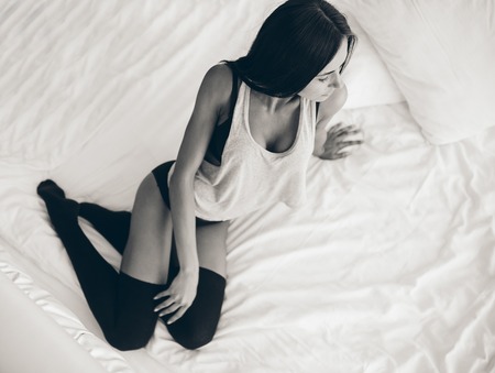 half-dressed beautiful young girl lies on a white bedの写真素材