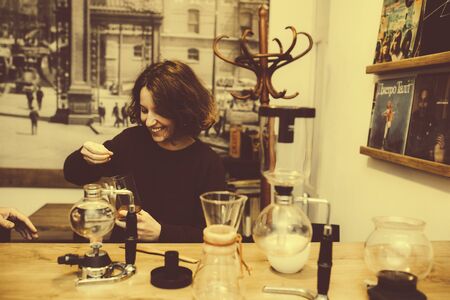 Vintage couple preparing coffee with vacuum coffee maker.Coffee shop.  Vintage toned