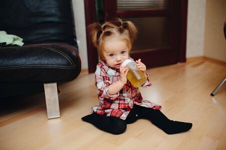 Sweet baby girl sitting on the floor and drinking teaの写真素材