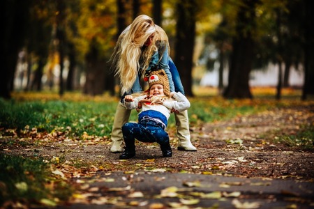 mother and daughter having fun in autumn parkの写真素材