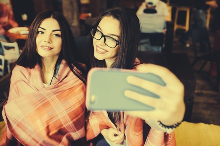two close girlfriends want to make a selfie in the cafe on memoryの写真素材