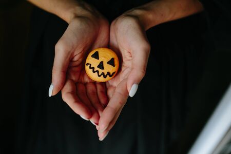 woman holding a biscuit for Halloween on black backgroundの写真素材