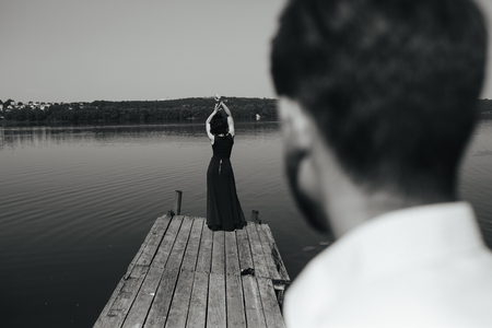 beautiful young couple spends time on the wooden pier on the lakeの写真素材