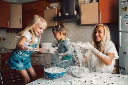 mother and children playing on kitchen with flourの写真素材