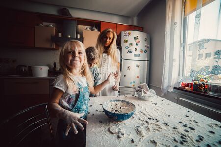 mother and children playing on kitchen with flourの写真素材
