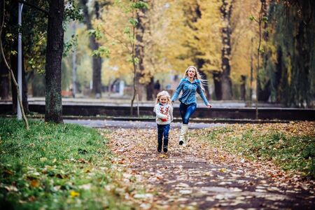 mother and daughter having fun in autumn parkの写真素材