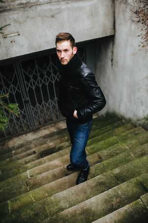 A man dressed in jeans and black jacket on autentic stairs