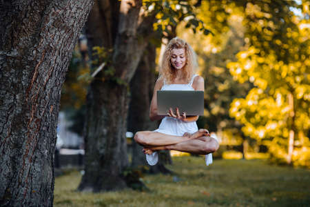 beautiful girl levitates in nature with laptopの写真素材