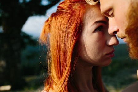 beautiful couple standing on a hill and gently hugging each otherの写真素材