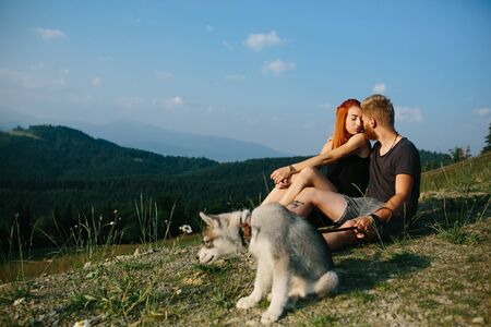 beautiful couple sits on a hill and hugging each otherの写真素材