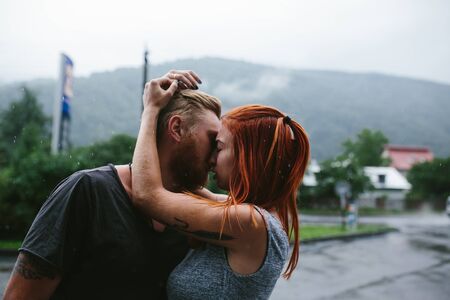 beautiful couple hugging on outside in the rainの写真素材