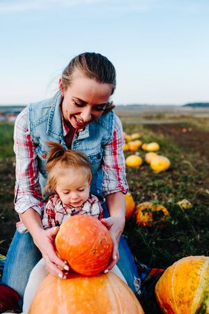Mother and daughter sitting on pumpkins, Halloween eveの写真素材
