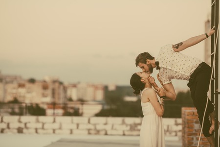 beautiful couple together on the roof of a tall buildingの写真素材