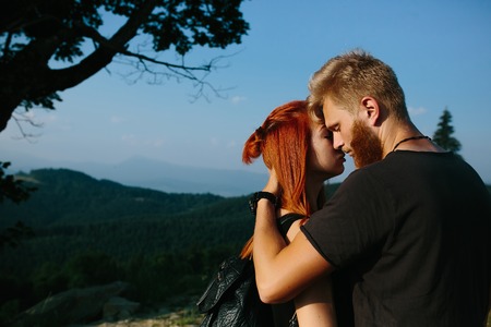 beautiful couple standing on a hill and gently hugging each otherの写真素材
